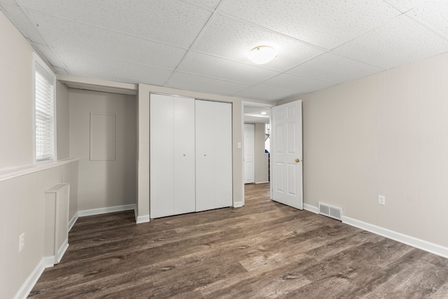 unfurnished bedroom with a closet, a drop ceiling, and dark hardwood / wood-style floors