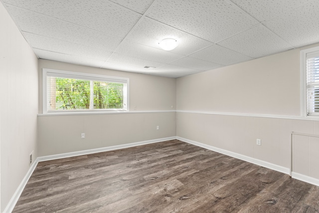 spare room with a paneled ceiling and dark hardwood / wood-style flooring