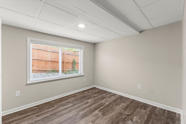 empty room featuring a paneled ceiling and dark wood-type flooring