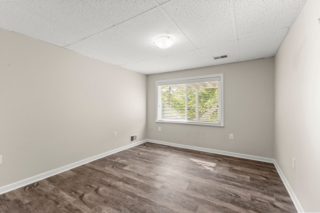 unfurnished room featuring a paneled ceiling and dark hardwood / wood-style floors