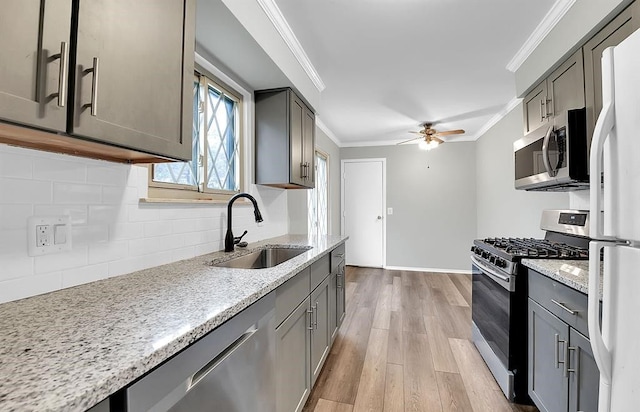 kitchen with sink, ornamental molding, light hardwood / wood-style floors, tasteful backsplash, and appliances with stainless steel finishes