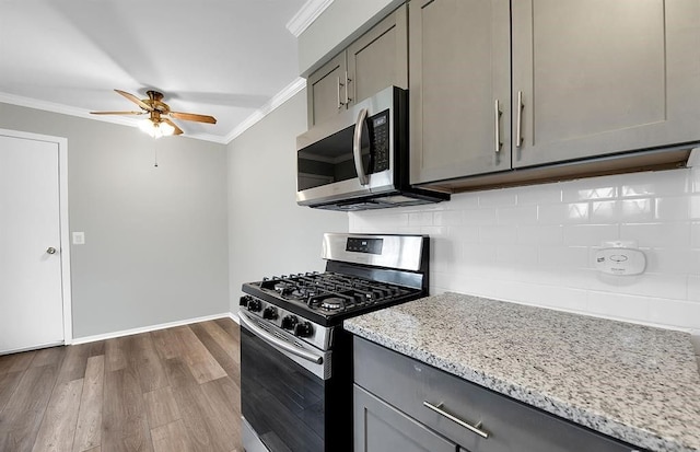 kitchen featuring stainless steel appliances, gray cabinets, backsplash, ornamental molding, and wood-type flooring