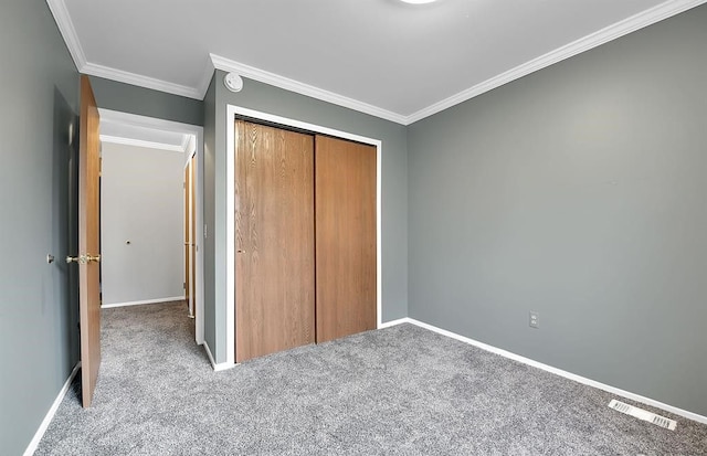 unfurnished bedroom with ornamental molding, a closet, and light carpet