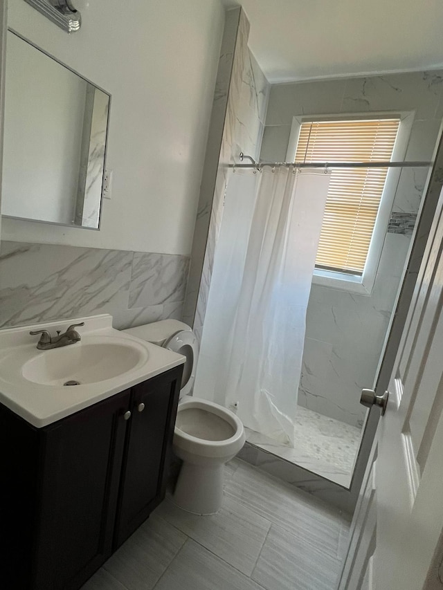 bathroom with tile walls, vanity, curtained shower, and toilet