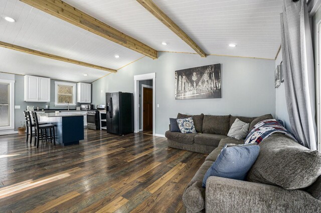 living room featuring dark hardwood / wood-style flooring and vaulted ceiling with beams