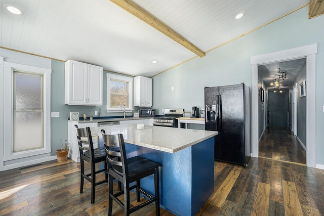 kitchen with lofted ceiling with beams, dark hardwood / wood-style floors, black appliances, a kitchen island, and white cabinets