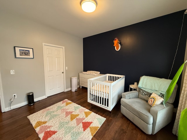 bedroom with dark wood-type flooring and a nursery area