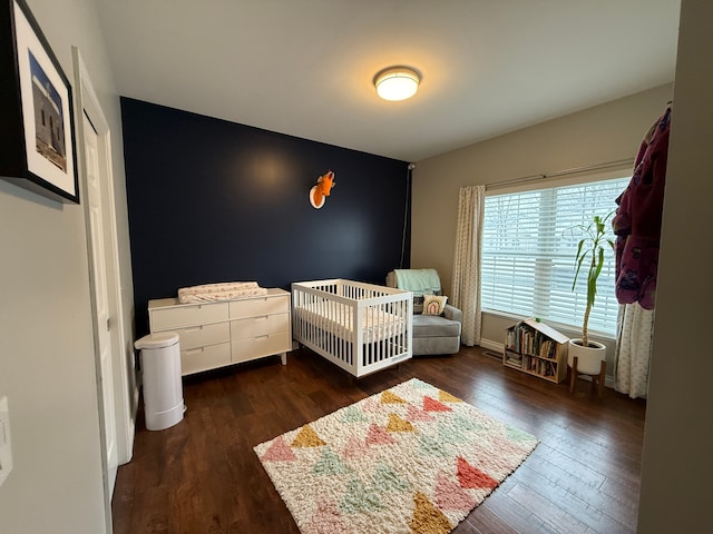 bedroom featuring dark hardwood / wood-style floors and a crib