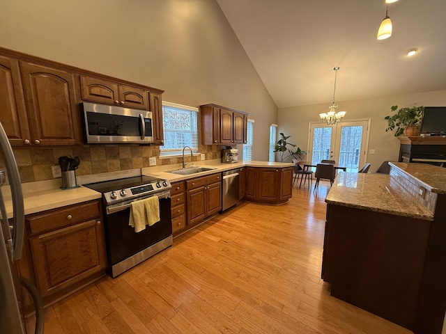 kitchen featuring tasteful backsplash, decorative light fixtures, sink, an inviting chandelier, and appliances with stainless steel finishes