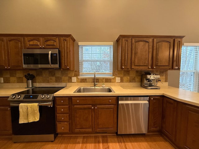 kitchen featuring light wood-type flooring, backsplash, sink, and stainless steel appliances