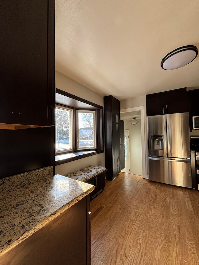 kitchen featuring appliances with stainless steel finishes, light hardwood / wood-style floors, and light stone countertops