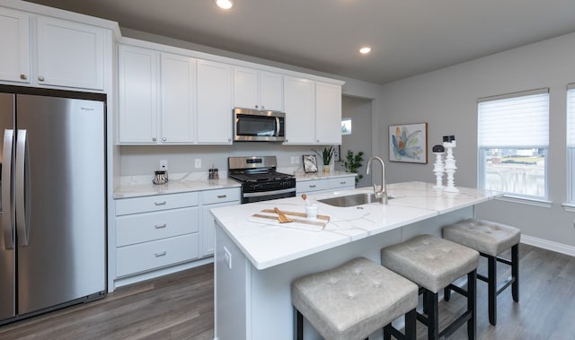 kitchen featuring dark hardwood / wood-style floors, a center island with sink, white cabinetry, appliances with stainless steel finishes, and sink