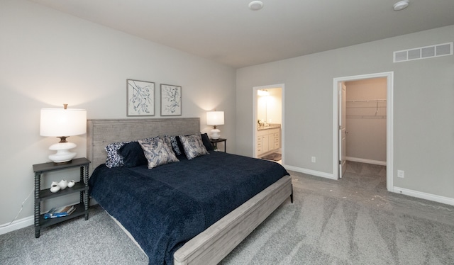 carpeted bedroom with a walk in closet, a closet, and connected bathroom