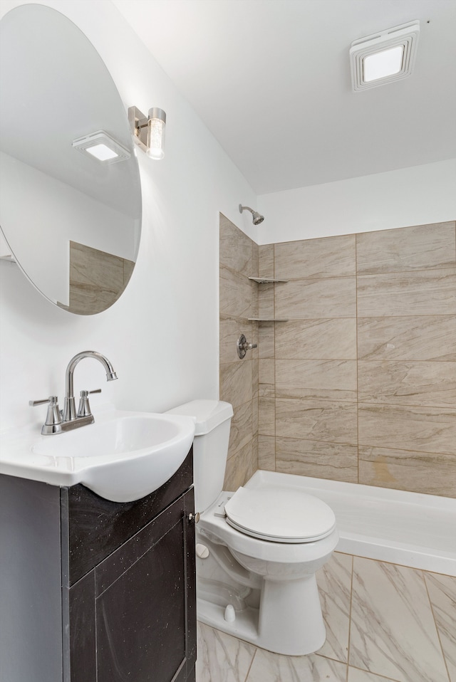 bathroom with vanity, tiled shower, and toilet