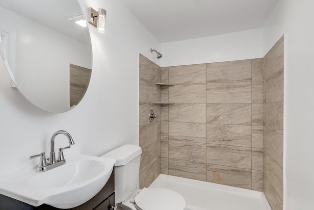 bathroom featuring tiled shower, vanity, and toilet