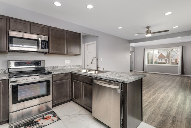 kitchen featuring stainless steel appliances, dark brown cabinets, sink, and kitchen peninsula