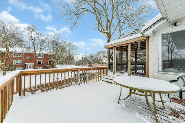 snow covered deck featuring a sunroom