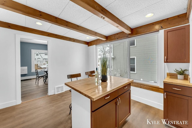 kitchen featuring light hardwood / wood-style floors, a center island, wood counters, and a kitchen bar