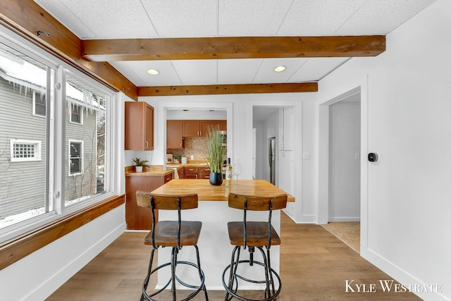 kitchen featuring light hardwood / wood-style floors, wood counters, backsplash, and a kitchen bar