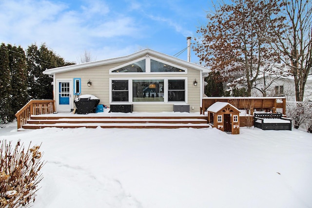 snow covered back of property with a deck