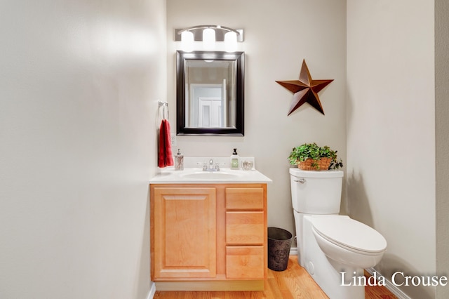 bathroom featuring toilet, hardwood / wood-style floors, and vanity