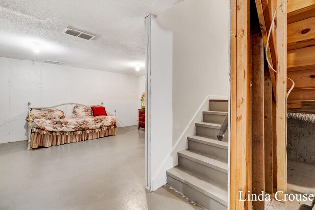 stairs with a textured ceiling and concrete flooring