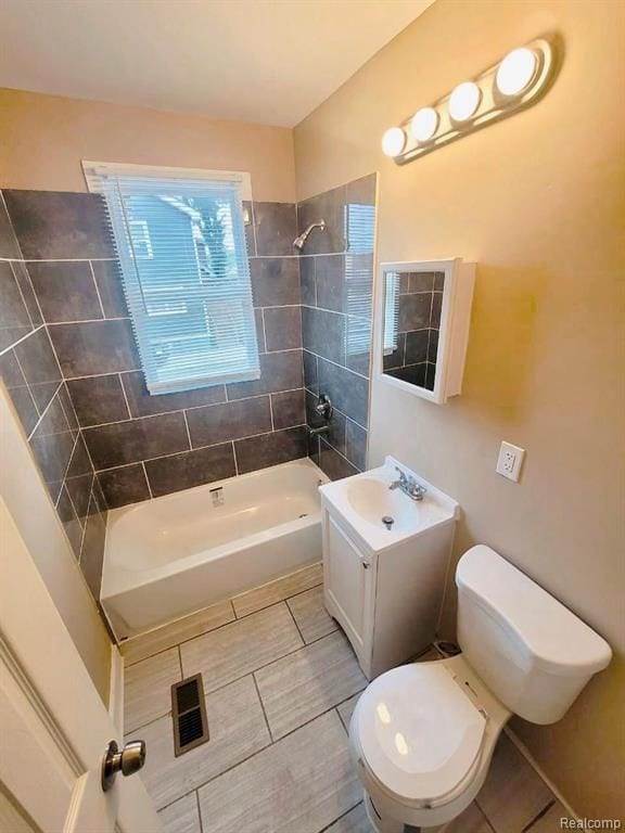 full bathroom featuring tiled shower / bath combo, toilet, and vanity