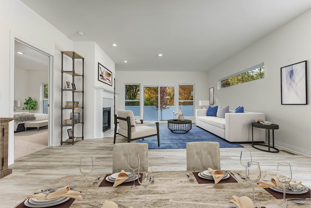 living room with light wood-type flooring, a tiled fireplace, and plenty of natural light