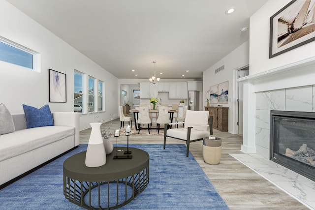 living room with a fireplace, light hardwood / wood-style floors, and a notable chandelier