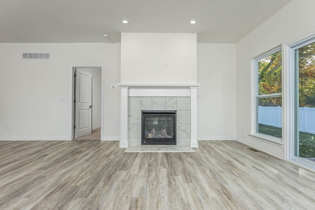 unfurnished living room featuring a tile fireplace and light hardwood / wood-style floors