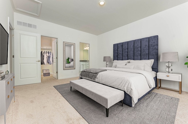 bedroom with light colored carpet, a spacious closet, ensuite bathroom, and a closet