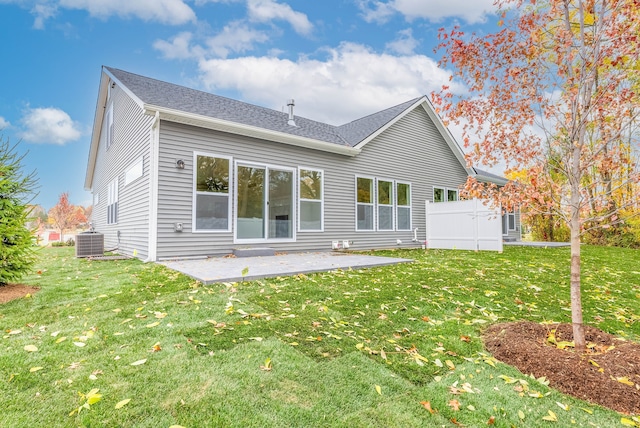 rear view of house with a patio, cooling unit, and a lawn