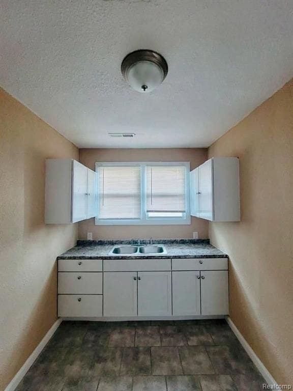 kitchen featuring sink, white cabinets, and a textured ceiling