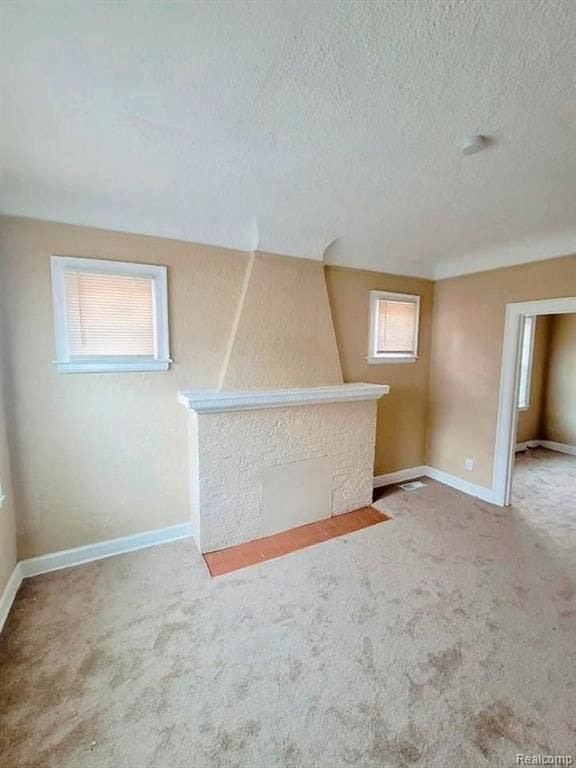 bonus room featuring a textured ceiling, carpet flooring, and plenty of natural light