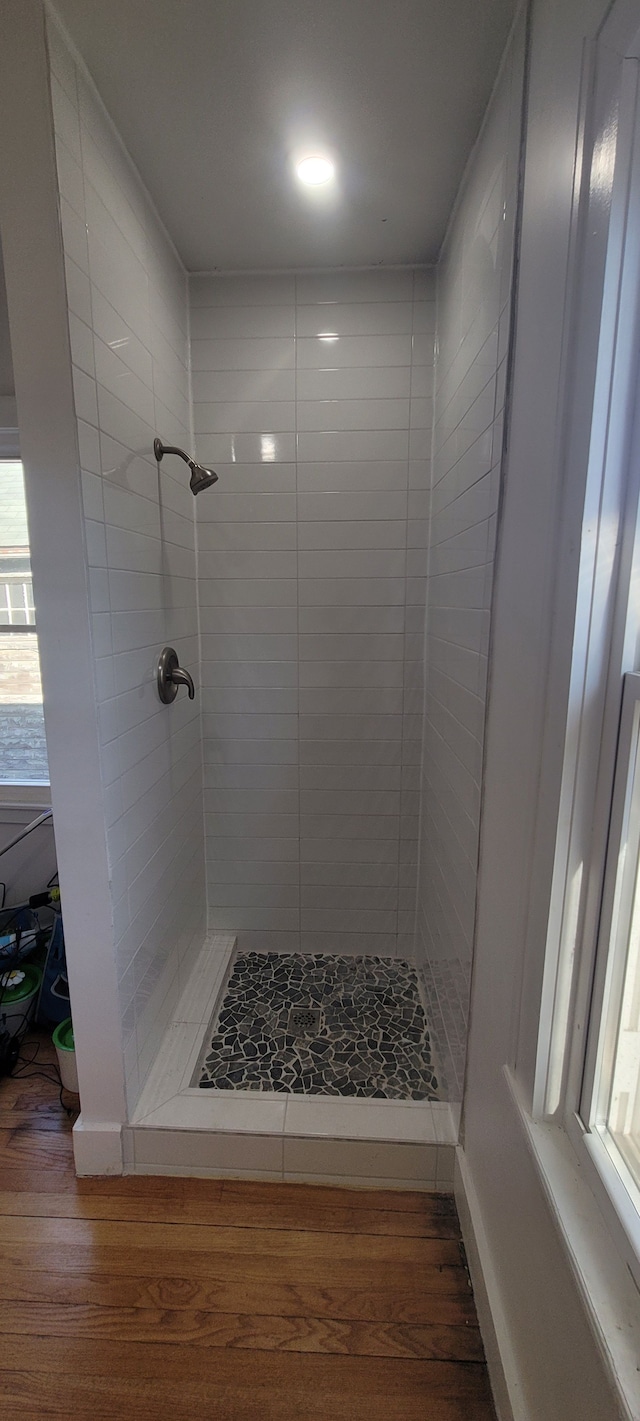 bathroom with a wealth of natural light, a stall shower, and wood finished floors