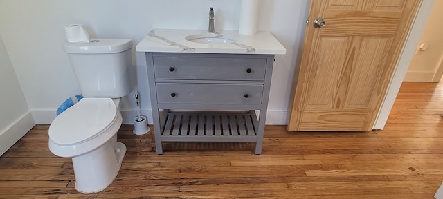 bathroom with toilet, vanity, and wood finished floors