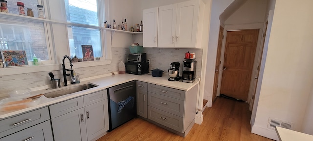 kitchen with gray cabinetry, open shelves, a sink, light countertops, and dishwashing machine