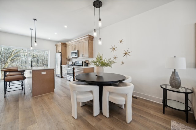 dining space with light wood-type flooring and sink