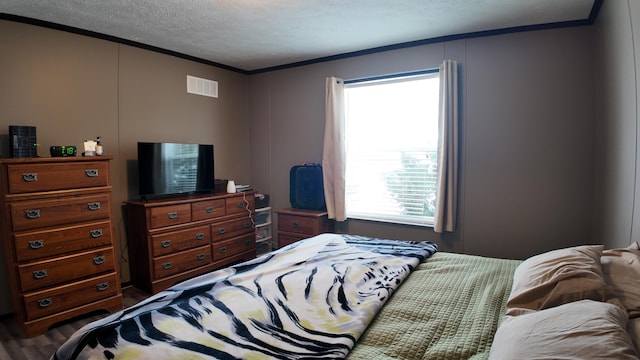 bedroom with a textured ceiling, ornamental molding, and multiple windows