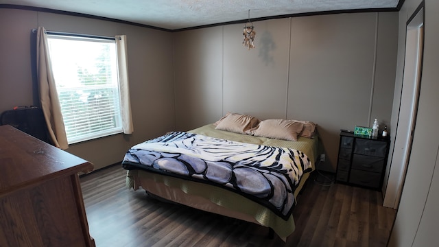 bedroom with a textured ceiling, ornamental molding, and dark wood-type flooring