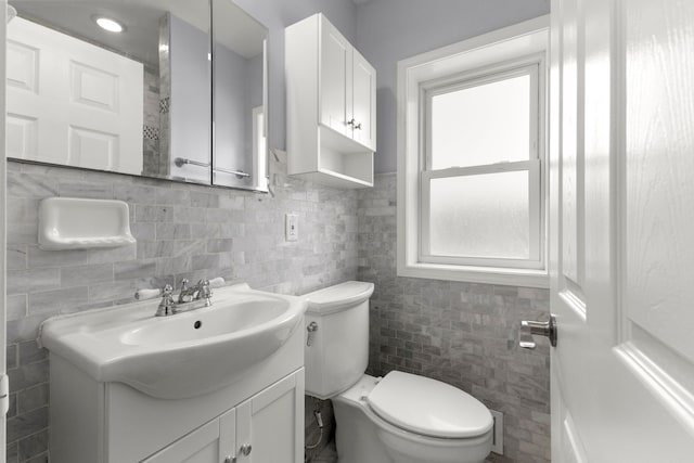 bathroom with toilet, vanity, and tile walls