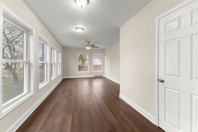 interior space with visible vents, baseboards, ceiling fan, and dark wood finished floors