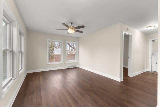 spare room with baseboards, a ceiling fan, dark wood-style floors, and visible vents