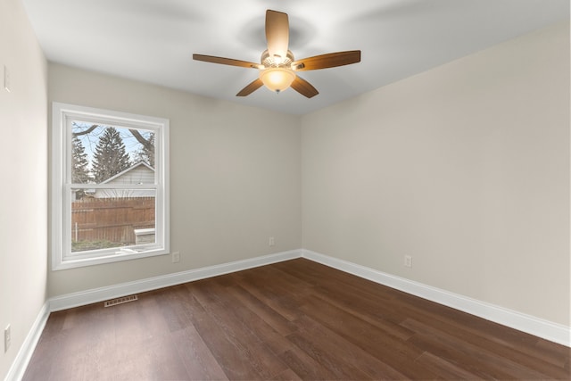empty room featuring dark wood-type flooring, baseboards, ceiling fan, and visible vents