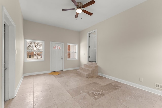 foyer featuring baseboards, ceiling fan, and visible vents
