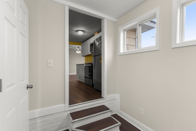 hallway featuring baseboards and dark wood-type flooring