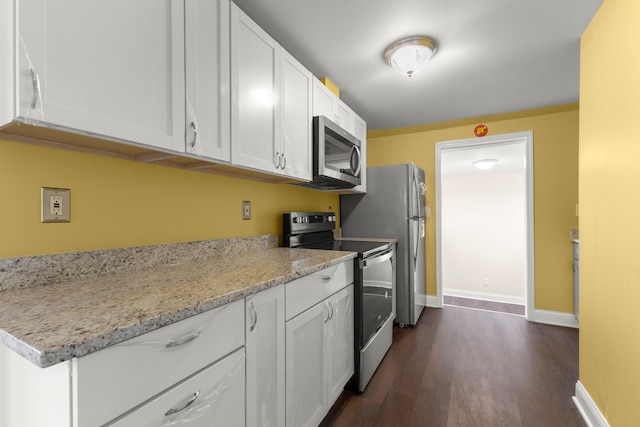 kitchen featuring dark wood-style flooring, appliances with stainless steel finishes, light stone counters, white cabinetry, and baseboards