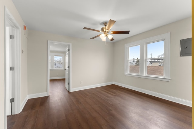 empty room with electric panel, dark hardwood / wood-style flooring, and ceiling fan