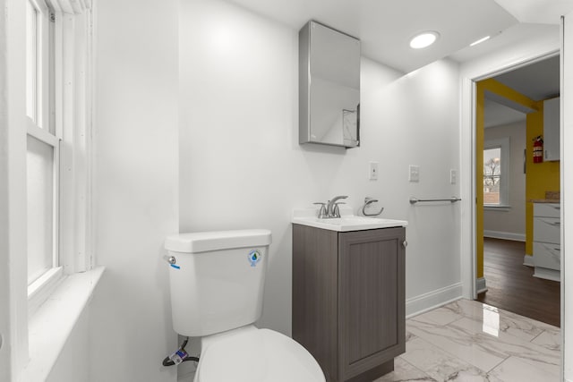 bathroom featuring vanity, marble finish floor, baseboards, and toilet