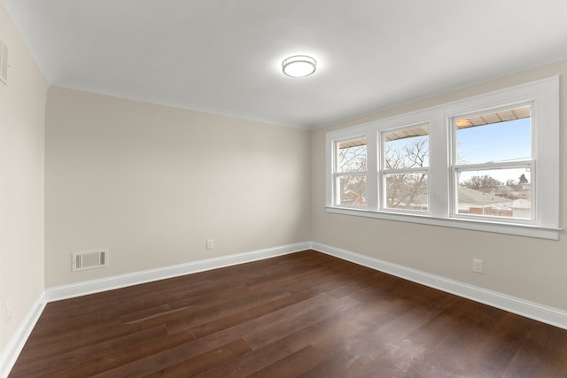spare room featuring baseboards, visible vents, and dark wood-type flooring